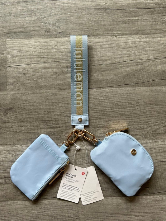 Two light blue pouches with a strap and tags on a wooden surface